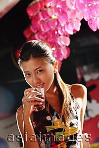 Asia Images Group - Young woman holding glass to mouth, looking at camera
