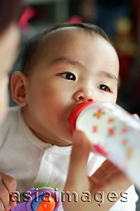 Asia Images Group - Baby girl drinking from bottle, looking away