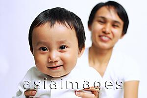 Asia Images Group - Baby boy smiling at camera, mother carrying him