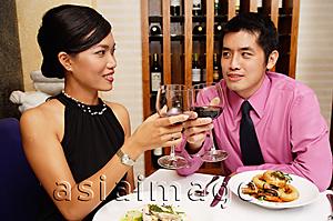 Asia Images Group - Couple in restaurant raising wine glasses for a toast