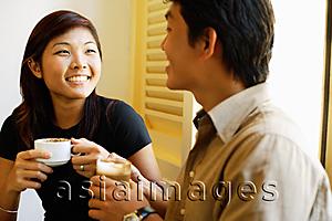 Asia Images Group - Couple sitting, holding coffee cups, side by side
