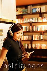 Asia Images Group - Young woman listening to music, holding CD, smiling