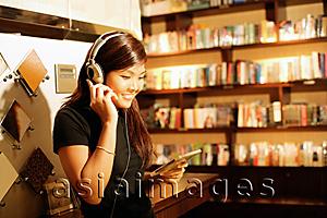 Asia Images Group - Young woman listening to music, smiling, holding CD