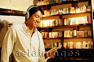 Asia Images Group - Young man listening to music, smiling, holding CD