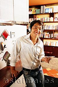Asia Images Group - Young man listening to music, smiling, looking at camera