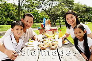 Asia Images Group - Family sitting at picnic table, looking at camera