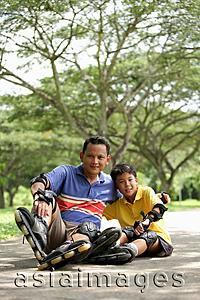 Asia Images Group - Father and son, sitting in park, wearing roller blades, looking at camera