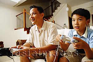 Asia Images Group - Father and son, side by side, playing video games