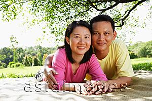 Asia Images Group - Couple on picnic mat, looking at camera