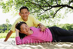 Asia Images Group - Couple on picnic mat, woman lying down, man sitting behind her