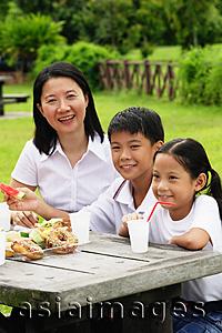 Asia Images Group - Mother with two children, sitting at picnic table, portrait