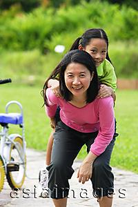 Asia Images Group - Mother giving daughter a piggyback, looking at camera