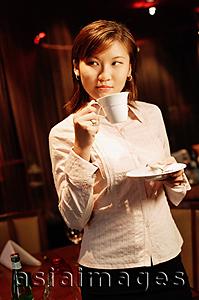 Asia Images Group - Woman holding cup and saucer, looking away
