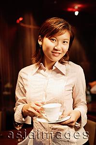 Asia Images Group - Woman holding cup and saucer, looking at camera
