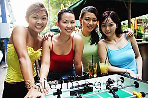 Asia Images Group - Young women posing next to foosball table