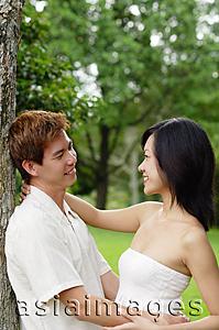 Asia Images Group - Couple leaning on tree, embracing, looking at each other
