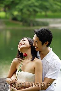 Asia Images Group - Couple embracing, woman holding rose stalk