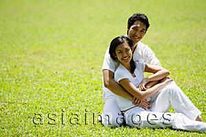 Asia Images Group - Couple embracing, sitting on grass, smiling at camera