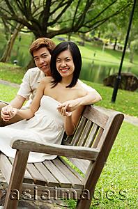 Asia Images Group - Couple sitting on park bench, looking at camera