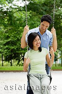Asia Images Group - Woman sitting on swing, man behind her