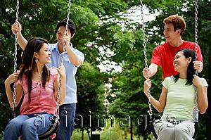 Asia Images Group - Women on swings, men standing behind them