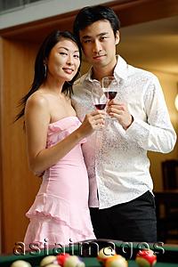 Asia Images Group - Couple standing side by side, holding wine glasses, looking at camera