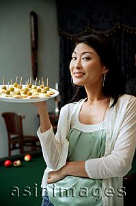 Asia Images Group - Woman holding tray of appetizers, smiling at camera