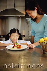 Asia Images Group -  Mother and daughter looking at plate of food, smiling