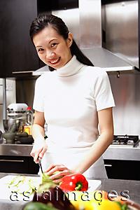 Asia Images Group - Woman cutting vegetables looking at camera, smiling