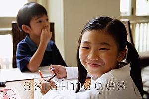 Asia Images Group - Children sitting at table, girl turning to smile at camera