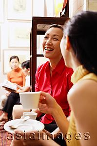 Asia Images Group - Women sitting, smiling, holding cups and saucers