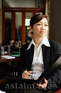 Asia Images Group - Businesswoman, sitting, holding pen and folder, looking away,