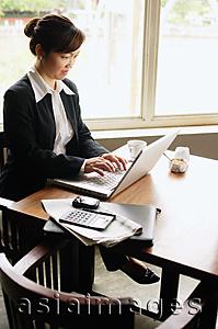 Asia Images Group - Businesswoman sitting at table using laptop