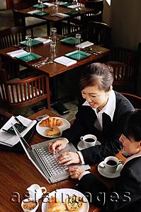 Asia Images Group - Businesswomen at cafe, using laptop