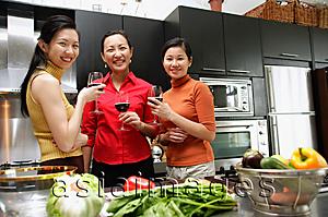 Asia Images Group - Three women in kitchen, holding wine glasses, looking at camera