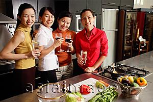 Asia Images Group - Four women in kitchen, holding wine glasses, smiling at camera