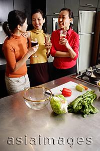 Asia Images Group - Women in kitchen, standing side by side, holding drinks