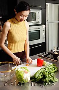 Asia Images Group - Woman in kitchen, cutting vegetables