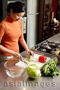 Asia Images Group - Woman cutting vegetables in kitchen