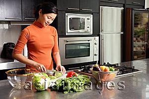 Asia Images Group - Woman cutting vegetables in kitchen, portrait