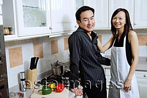 Asia Images Group - Man and woman standing in kitchen, smiling at camera