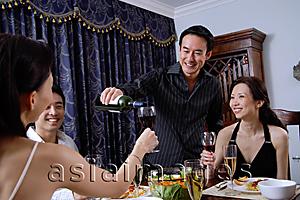 Asia Images Group - Couples having dinner party at home, man pouring wine for woman
