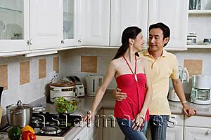 Asia Images Group - Couple standing in kitchen, smiling at each other, portrait