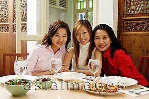 Asia Images Group - Three women sitting at restaurant table, smiling at camera