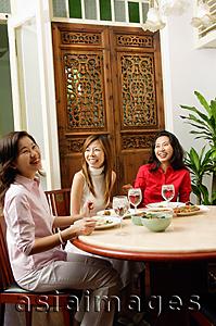 Asia Images Group - Three women having a meal at restaurant, laughing