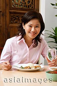 Asia Images Group - Woman in pink blouse having a meal, looking at camera