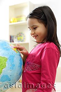 Asia Images Group - Young girl standing and looking at globe