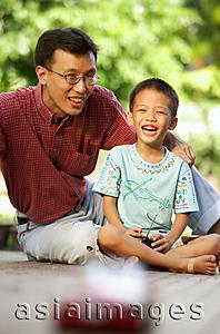 Asia Images Group - Son with remote control toy car, father next to him, smiling