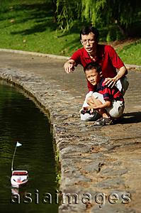 Asia Images Group - Father and son playing with remote control boat