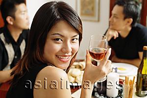 Asia Images Group - Woman with wine glass, looking over shoulder, smiling